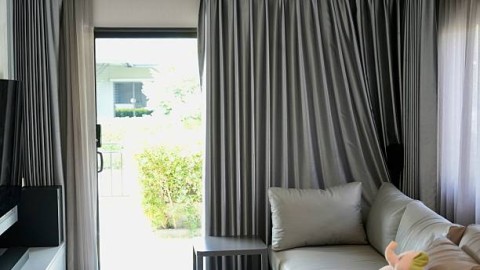 A modern, comfortable living room sliding glass door opening to a bright patio or garden.Gray L-shaped sofa with plush cushions in foreground, home interiors, real estate, modern living,home concept.