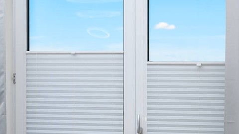 insulated balcony window with a view covered with gray pleats